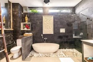 Bathroom 1: A cultural oasis with Balinese hand-carved window and mirror at Villa Carissa.