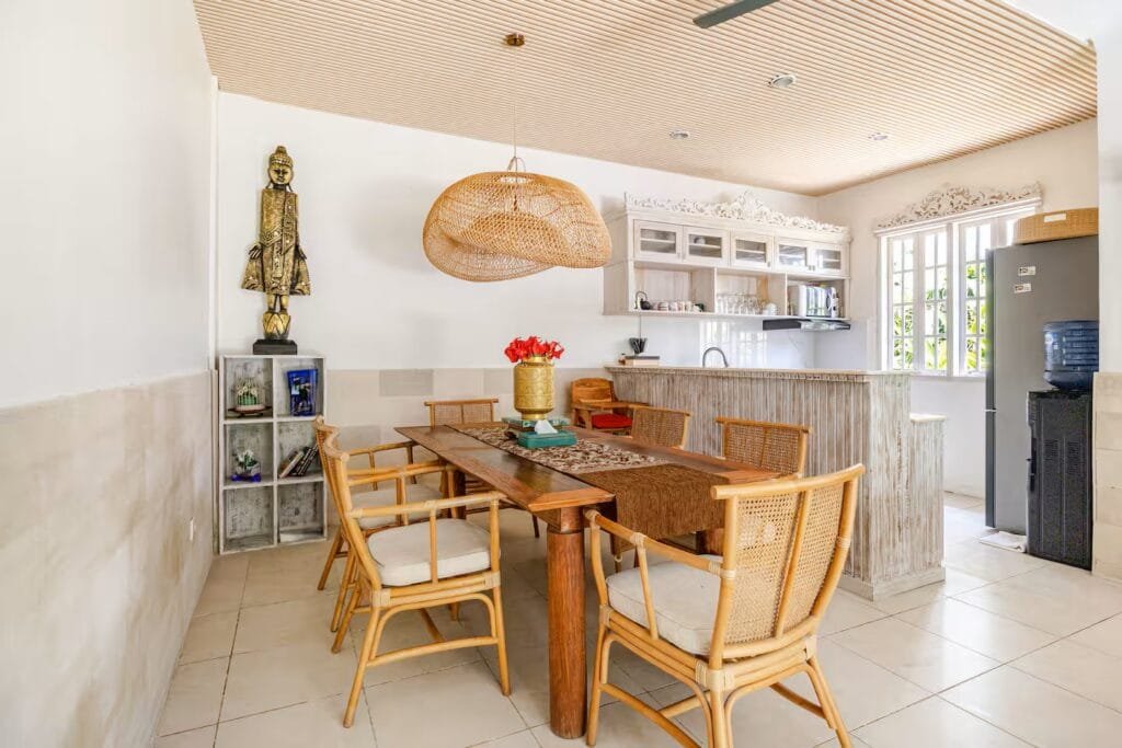 The villa features a bright open-plan dining area and a fully equipped kitchen. The wooden table and rattan chairs create a warm Balinese touch, perfect for family meals or friendly gatherings